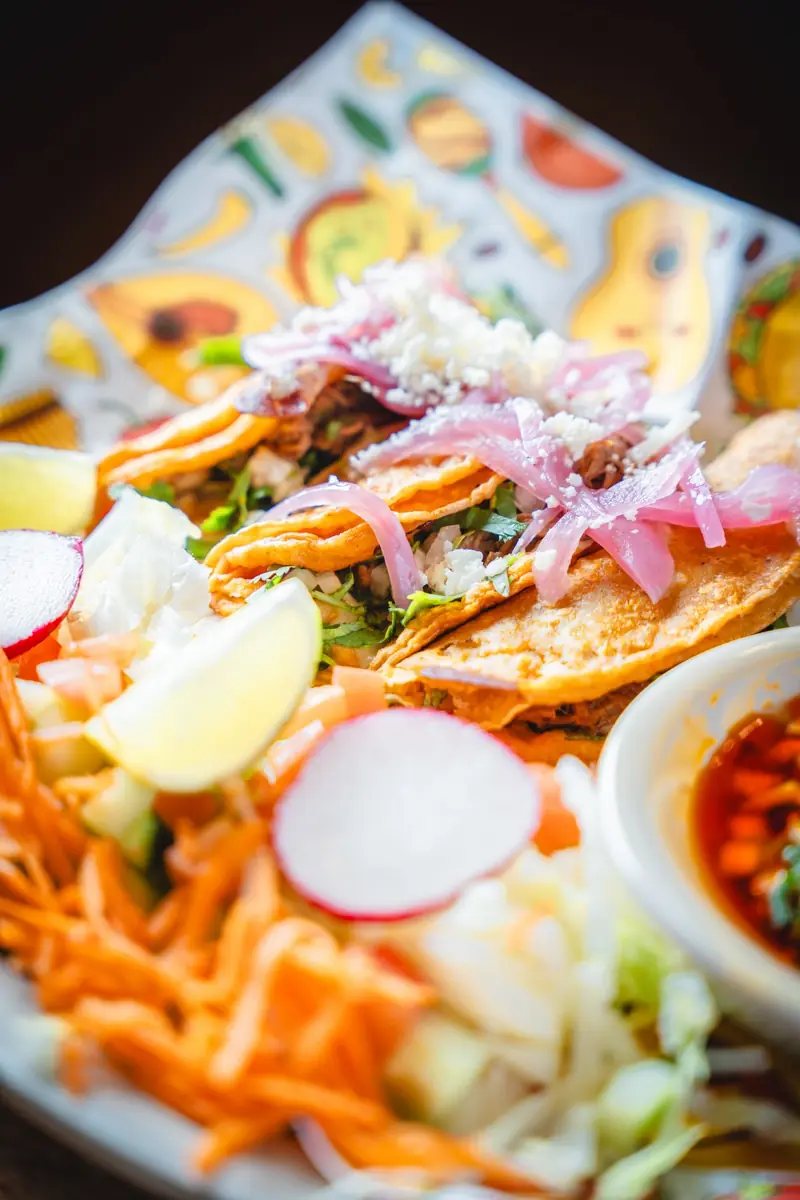 Crisp birria tacos with pickled onion, radish and carrot, with a cup of consome