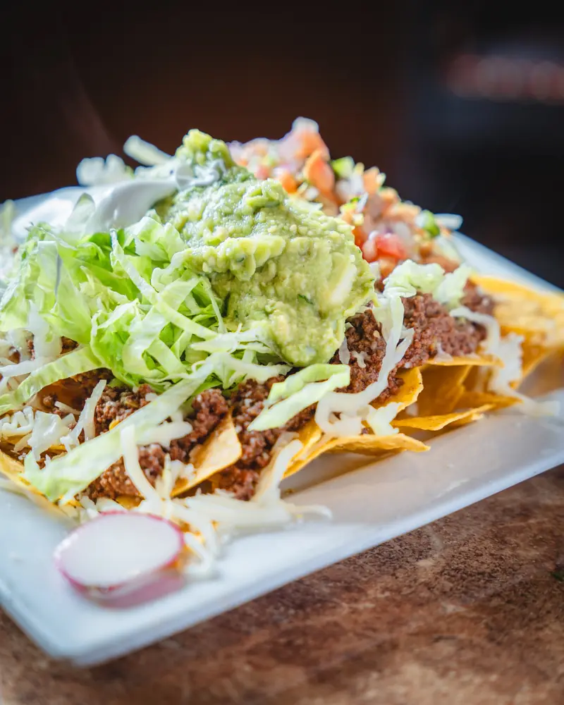 Nachos piled with seasoned beef, cheese, lettuce, guacamole and pico de gallo